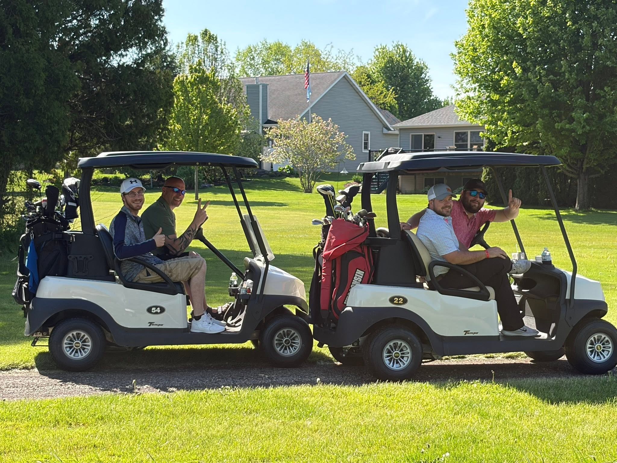 Four smiling golfers in two golf carts at Columbus Country Club